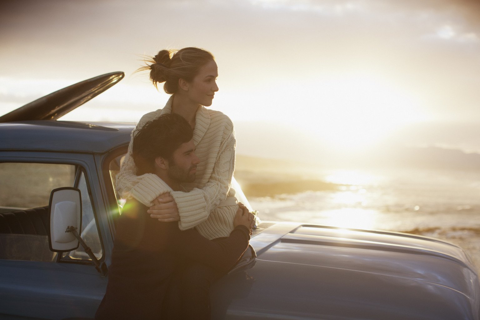 Serene couple hugging on truck at beach
